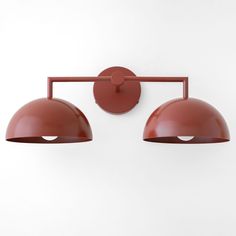 two red lights mounted to the side of a white wall next to each other on a light fixture