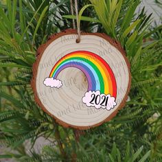 a wooden ornament hanging from a tree with a rainbow painted on it's side