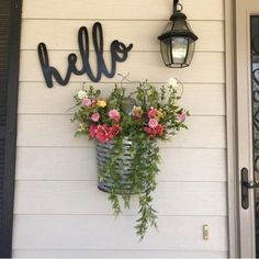 a basket with flowers hanging from the side of a house next to a light fixture