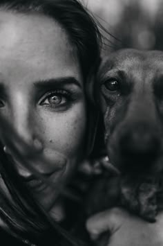 black and white photograph of a woman holding a dog's face in front of her