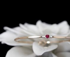 "My signature solitaire bangle, a timeless bracelet featuring a vibrant lab created Ruby, July's traditional birthstone. These gems exhibit a vivid and saturated magenta pink color and a semi-translucent body. The bracelet features a locking hook and eye closure. The gems used in this design measure approximately 3.5mm.  METAL OPTIONS  Select your choice from the dropdown menu. If the Two Toned option is selected please use the personalization field to specify your combination.  FINISH OPTIONS Classic Birthstone Bracelets For Anniversary, Wedding Fine Jewelry Bracelet With Birthstone, Classic Gemstone Bangle For Anniversary, Adjustable Fine Jewelry Bangle For Anniversary, Stackable Round Band Bracelets For Anniversary, Red Jewelry With Tension Setting For Anniversary, 14k Gold Bangle For Anniversary, Anniversary 14k Gold Bangle With Single Diamond, 14k Gold Bangle With Single Diamond For Anniversary