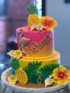 there is a three tiered cake decorated with flowers and an flamingo on top