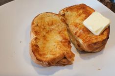 two pieces of toast on a white plate with butter