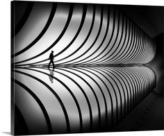 black and white photograph of a person walking in front of a large wall with lines on it