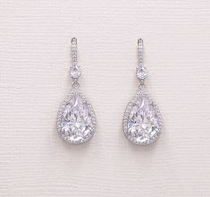 Add brilliant sparkle with these classically designed framed cubic zirconia teardrop wedding earrings set in brilliant silver. Perfect for any special occasion, these wedding earrings feature a CZ encrusted French hook with a dangling teardrop for a truly unique look!  DETAILS * High quality cubic zirconia.  * Earrings measure 1 1/4 inches long. * Necklace is adjustable from 16 inches to 18 inches long, pendant measures 1 1/4 inches. * Perfect for brides, bridesmaids, mother of the bride, MOH, prom, or any special occasion.  * Finish: silver, gold or rose gold. * Hypoallergenic, lead-free & nickel-free. ADDITIONAL LENGTH WITH EXTENDER * Necklace extender available here: https://www.etsy.com/listing/1527588142/extender-for-necklace-clasp-extender?ref=listings_manager_grid * Bracelet extende White Gold Cubic Zirconia Teardrop Earrings For Wedding, Cubic Zirconia Teardrop Earrings With Sparkling Stones, Teardrop Cubic Zirconia Bridal Earrings, Formal Teardrop Earrings With Halo Design, Teardrop Cubic Zirconia Diamond Earrings With Pearl Drop, Teardrop Pearl Drop Earrings In Cubic Zirconia, Pear-shaped Teardrop Earrings With Prong Setting For Wedding, Pear-shaped Teardrop Earrings With Halo Design For Wedding, Cubic Zirconia Teardrop Earrings For Anniversary