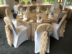 a banquet room set up with white chairs and gold table cloths for an elegant event