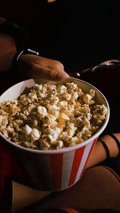 a person holding a bowl of popcorn in their hand