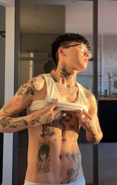 a man with tattoos on his chest holding something in one hand and looking up at the sky