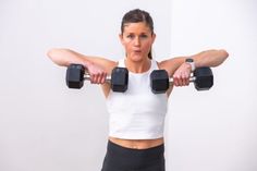 a woman holding two dumbbells in front of her face