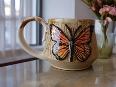 a coffee cup with a butterfly painted on it