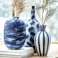 two blue and white vases sitting next to each other on top of a table