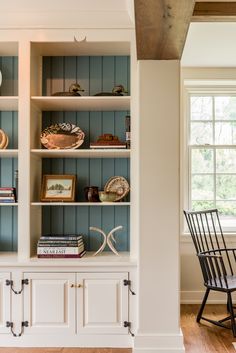 a white bookcase with two chairs in front of it