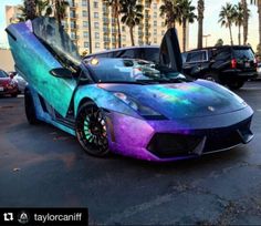 a very colorful car parked in a parking lot next to palm trees and tall buildings