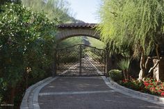 a gated driveway leading into a lush green park