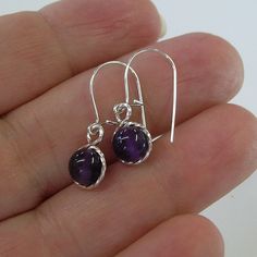 "Smooth purple amethyst 6mm beads, surrounded by sterling silver twist wire. Sweet! Small enough to wear every day, these earrings measure 7/8\" long including the sterling silver earwires. Amethyst is the February birthstone. This would make a perfect, affordable gift for that February girl, young or old! Also available in 14kt gold filled." Pierced Amethyst Crystal Earrings, Handmade Purple Sterling Silver Earrings, Purple Teardrop Crystal Earrings In Sterling Silver, Nickel-free Purple Dangle Hoop Earrings, Silver Amethyst Earrings With Ear Wire, Purple Nickel-free Dangle Hoop Earrings, Nickel-free Round Purple Earrings, Nickel Free Amethyst Dangle Earrings, Amethyst Dangle Earrings For Jewelry Making