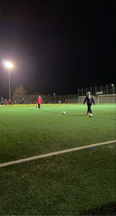 some people are playing soccer on a field at night