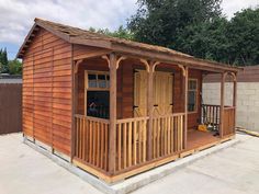 a small wooden building sitting in the middle of a yard next to a fence and trees