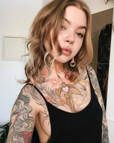 a woman with tattoos on her chest posing for the camera