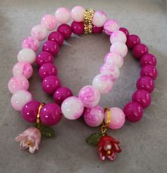 Two beautiful bracelets, 10MM glass beads with cute flowers charms. Flower-shaped Heart Beads Bracelets For Gifts, Flower Shaped Bracelets With Heart Beads For Gifts, Heart Beads Flower Bracelet As Gift, Flower-shaped Bracelet With Heart Beads For Gifting, Pink Bracelets With Flower Charm And Round Beads, Pink Beaded Flower Charm Bracelet, Pink Flower-shaped Stretch Bracelet With Colorful Beads, Pink Flower-shaped Stretch Bracelet Gift, Pink Flower Stretch Bracelet Gift