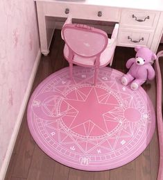 a pink teddy bear sitting on the floor next to a desk and chair in a room