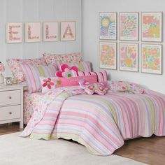 a bedroom with pink and green bedding and pictures on the wall