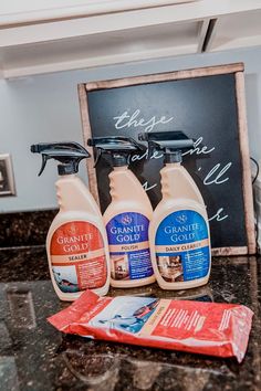 three bottles of cleaner sitting on top of a counter