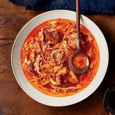 a bowl of meat and tomato soup with a spoon