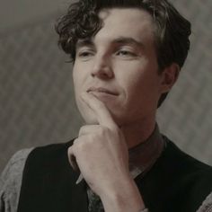 a young man with curly hair is looking at the camera while wearing a black vest