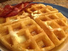 two waffles on a plate with bacon and syrup