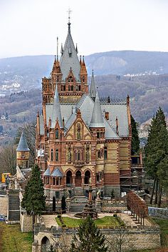 an old building with many towers on top of it's sides and trees in the foreground