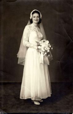 an old black and white photo of a woman in a wedding dress holding a bouquet