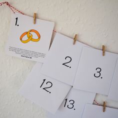 several pieces of paper hanging on clothes pegs with numbers and rings attached to them