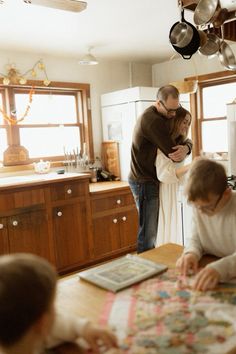 a man and woman standing in a kitchen next to a table with children on it