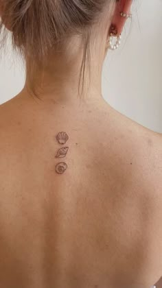 the back of a woman's neck with three seashells tattooed on it