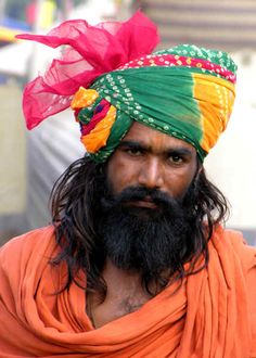 a man with a long beard wearing an orange turban and colorful headdress