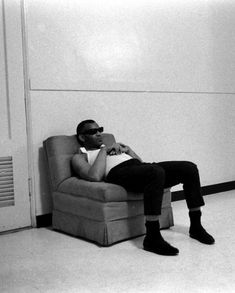 a black and white photo of a man sitting in a chair with his legs crossed