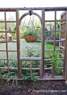 an open wooden window with a hanging planter in the center and plants growing inside