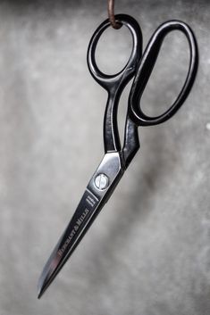 a pair of black scissors hanging from a cord