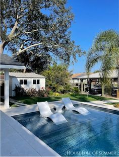 an empty swimming pool with lounge chairs in the foreground and houses in the background