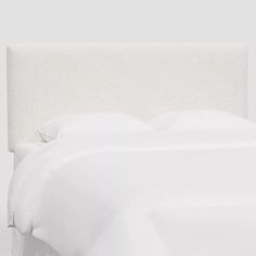 the headboard is made up with white linens and pillows on it's sides