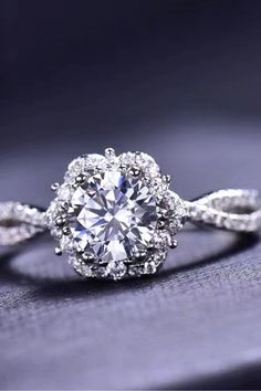 an engagement ring with a diamond center surrounded by white diamonds on a purple cloth background