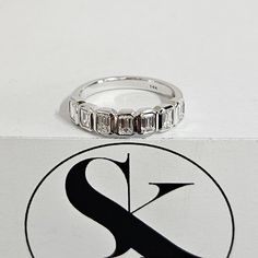 a diamond ring sitting on top of a white box next to a black and white logo