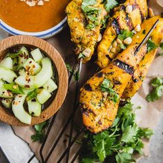 grilled chicken on skewers with garnishes and dipping sauce