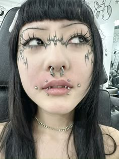 a woman with black hair and piercings on her nose