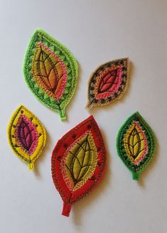 four embroidered leaves on a white surface