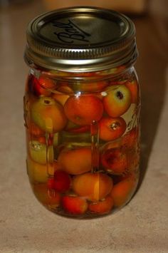 a jar filled with lots of oranges on top of a table