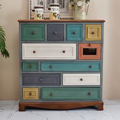 a multicolored chest of drawers in front of a potted plant on top of a table