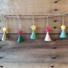 small ceramic christmas trees hanging from string on wooden planks with stars and polka dots