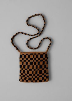 a black and brown checkered purse on a gray background with a long cord attached to it