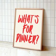 a sign that says, what's for dinner? on the floor next to a tiled wall